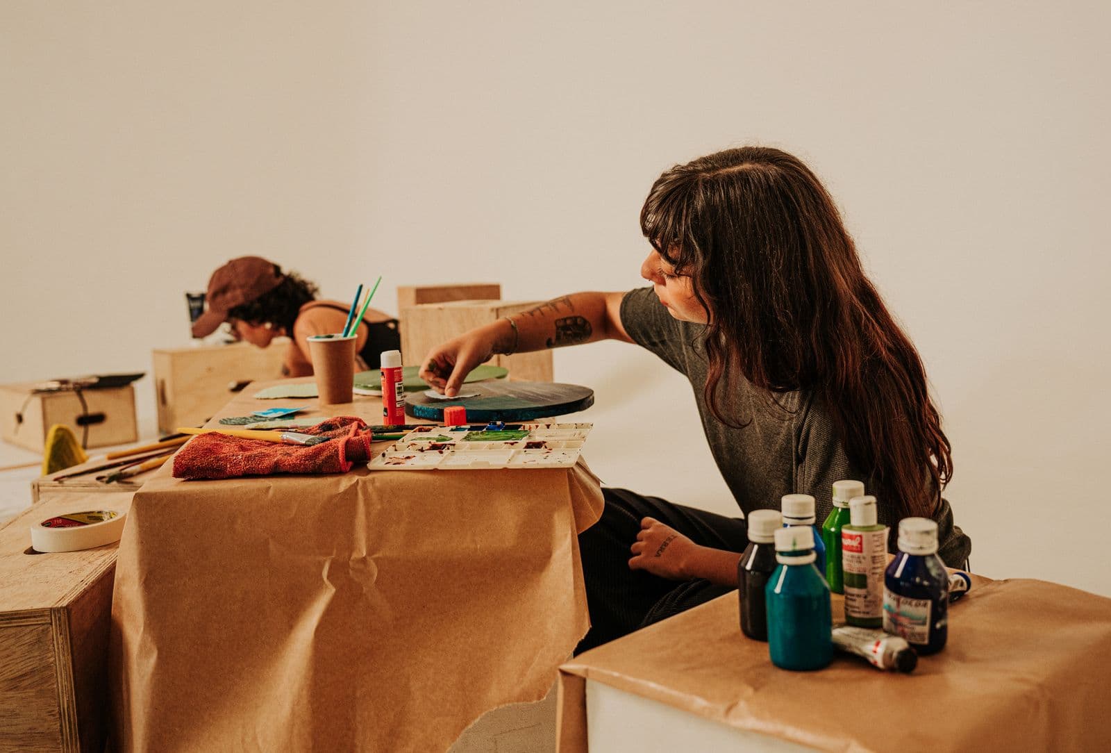 Two people working side by side over a shared studio table.