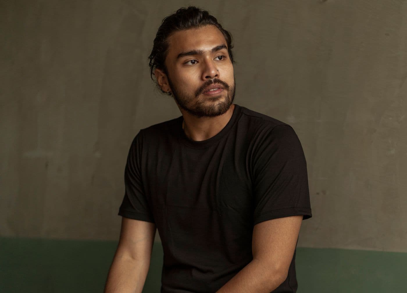 A person wearing a plain black t-shirt, lit from the side.